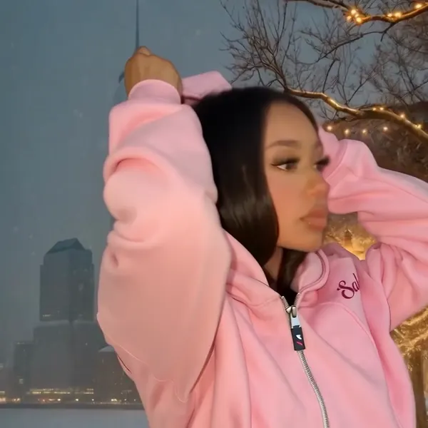 Model zipping the pink hoodie all the way up over her face